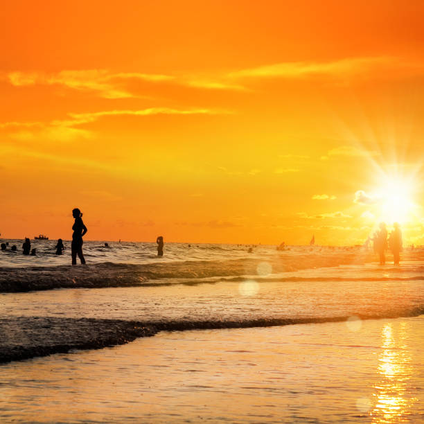 istock silhouetted people on beach over orange colored sunset sky 1173024153