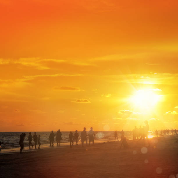 istock silhouetted people on beach over orange colored sunset sky 1173024155