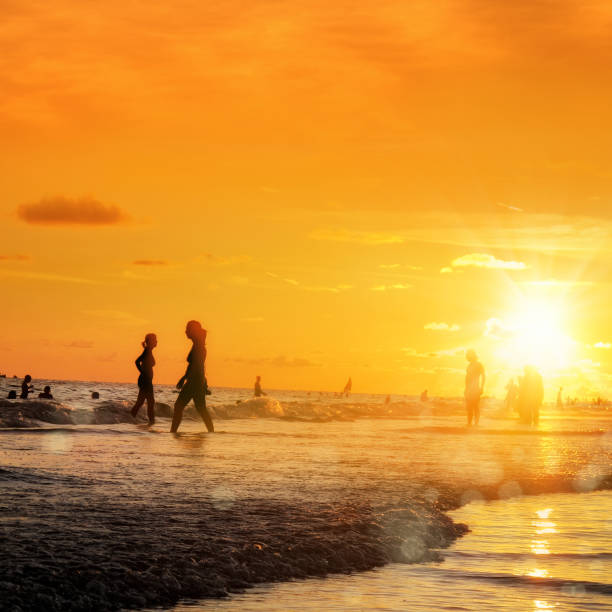 istock silhouetted people on beach over orange colored sunset sky 1173024335