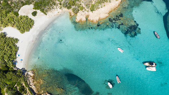 View from above, stunning aerial view of some boats and luxury yachts floating on a turquoise water. Maddalena Archipelago National Park, Sardinia, Italy.