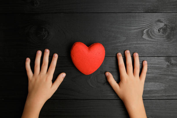 istock red heart in hands on a dark background 1173032236