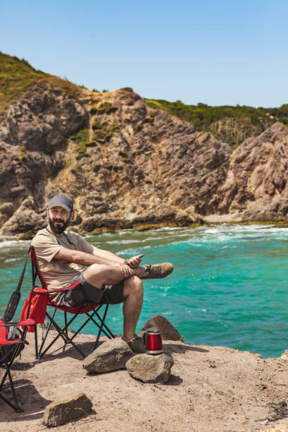 istock Man sitting in camping chair on the beach 1173033424