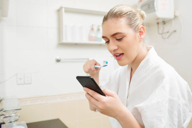 istock Woman checking phone and brushing teeth 1173045472
