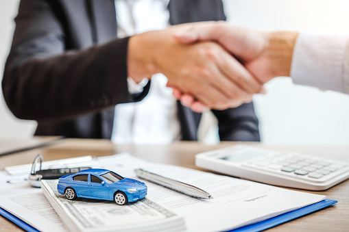 Sale agent handshake deal to agreement successful car loan contract with customer and sign agreement contract  Insurance car concept.