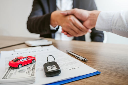 Sale agent handshake deal to agreement successful car loan contract with customer and sign agreement contract  Insurance car concept.