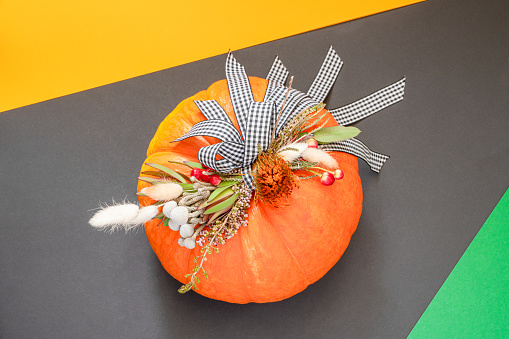 Halloween or Thanksgiving background. Autumn composition in pumpkin with ribbons and dried flowers with copy space.