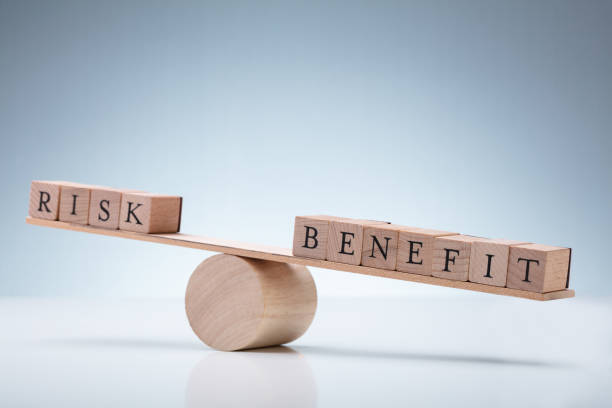 Wooden Block With Risk And Benefit Wooden Block On Seesaw Close-up Of Risk And Benefit Wooden Blocks On Seesaw Against Reflective Desk Risk taking stock pictures, royalty-free photos & images