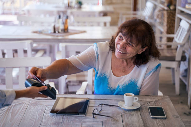 istock Contactless payment with NFC technology at a cafeteria. Attractive active senior woman resting in a cafe while daily running her business - stock photo 1173067392