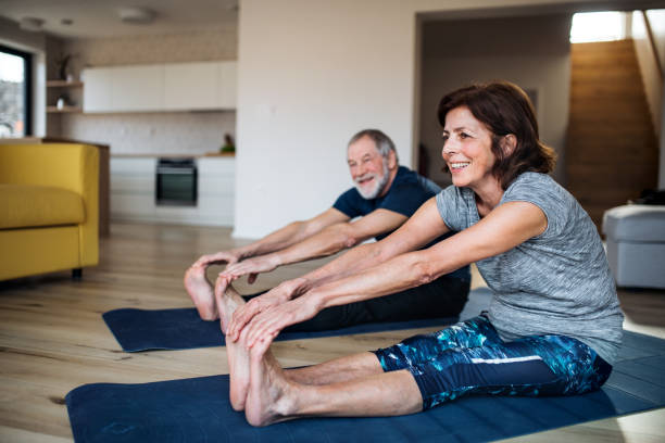 una pareja de ancianos en casa, haciendo ejercicio en el suelo. - action senior adult lifestyles couple fotografías e imágenes de stock