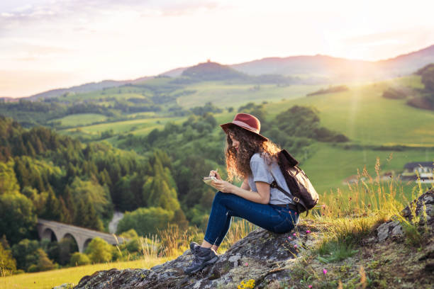 젊은 관광 여성 여행자는 자연에 앉아, 메모를 작성 배낭. - travel nature rural scene outdoors 뉴스 사진 이미지