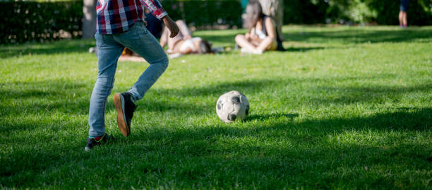 Rear view of unrecognizable boy playing soccer in public park, Nikon Z7