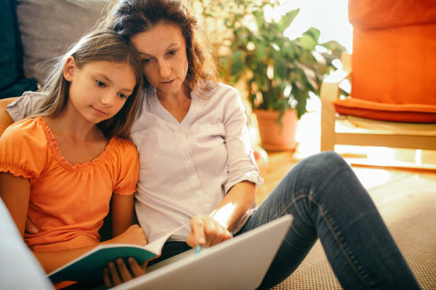 istock Girl doing homework with her mother at home 1173080189