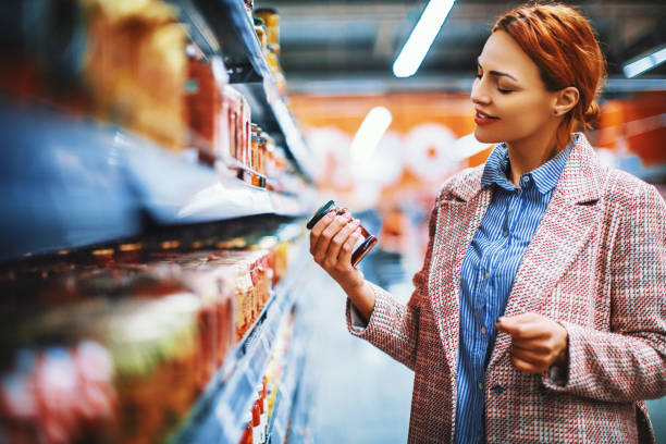 Reading nutrition label on the package at supermarket. Young woman reading nutrition label at package of Sun-dried tomatoes at supermarket. convenience food photos stock pictures, royalty-free photos & images