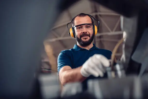 Photo of Factory worker operating band saw cutting machine