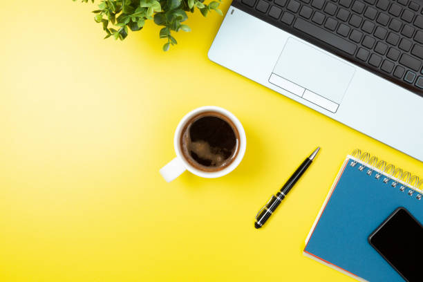 istock Laptop, notebook, smartphone, coffee and pen on yellow background. Office desk table with modern accessories 1173091604