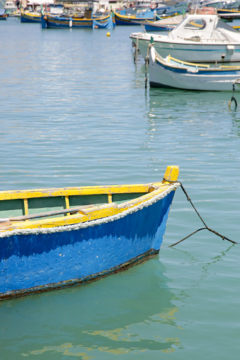 Small blue fishing boat in the clean water, water bay in Marsaxlokk, Malta's largest fishing village
