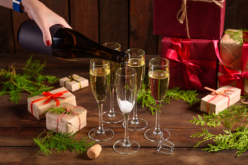 Christmas holiday table with glasses and a bottle of wine of champagne. Eve of new year, preparation and laying of a wooden holiday table