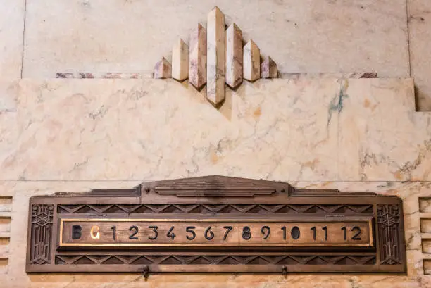 An Art Deco styled elevator floor indication made from brass set into a marble wall