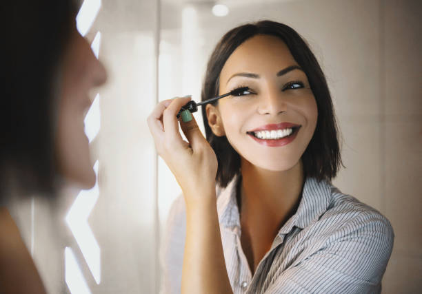 I'm getting ready for work. Beautiful woman applying mascara in front of the mirror in the bathroom. She's getting ready for work. mascara wands stock pictures, royalty-free photos & images