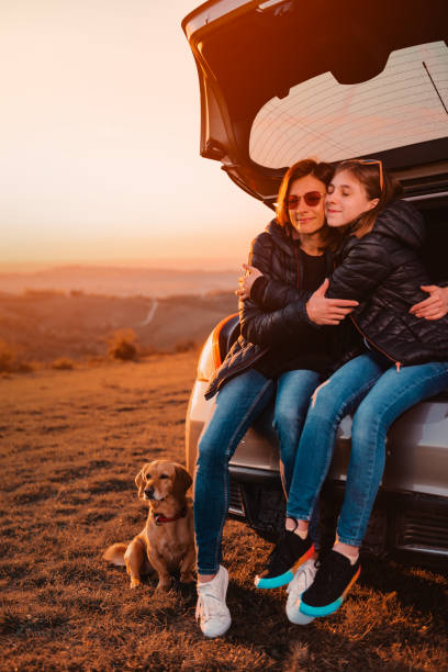 istock Daughter embracing mother while sitting in car trunk 1173101047