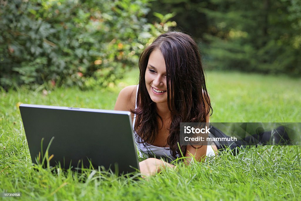Ragazza felice con computer portatile nel prato verde - Foto stock royalty-free di 20-24 anni