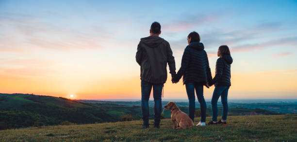 famiglia con cane che si abbraccia mentre si trova sulla collina - camp hill foto e immagini stock