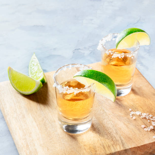 istock Golden tequila shots with lime slices and salt, with copy space, square image 1173102357
