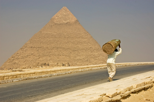 a young Arab man prays against the backdrop of the great pyramid of Cheops in Egypt. October 16, 2022. Giza, Egypt