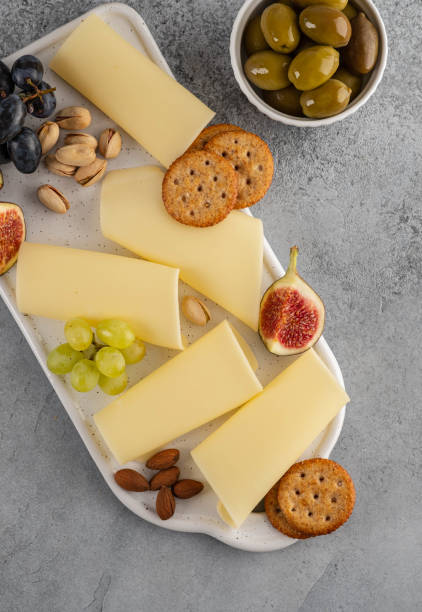 istock Cheese slices on white board with honey, figs, olives, grapes. 1173105827