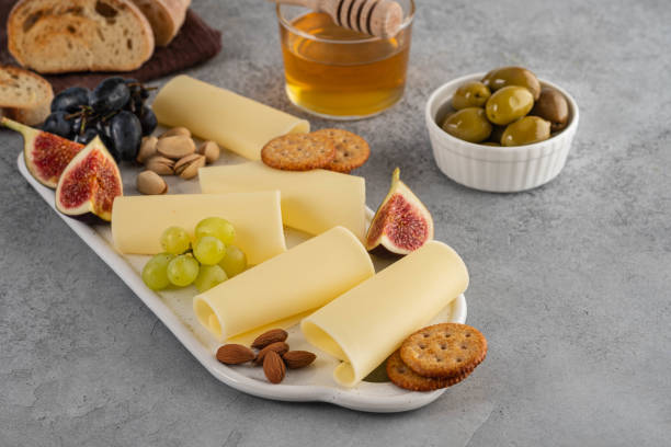 istock Cheese slices on white board with honey, figs, olives, grapes. 1173105865