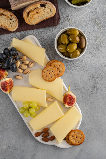 istock Cheese slices on white board with honey, figs, olives, grapes. 1173105884
