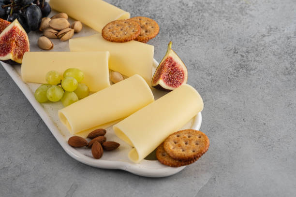istock Cheese slices on white board with honey, figs, olives, grapes. 1173105898