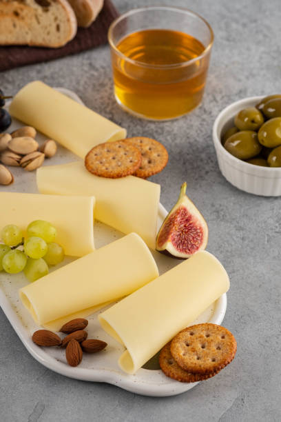 istock Cheese slices on white board with honey, figs, olives, grapes. 1173105906