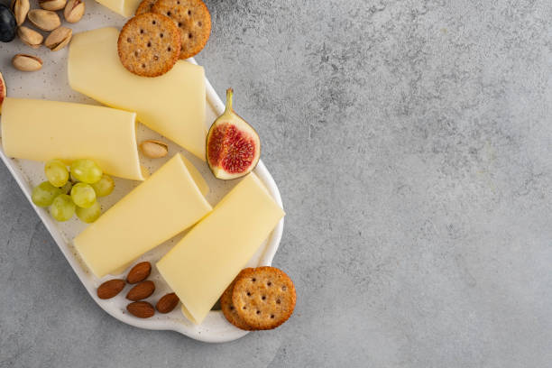 istock Cheese slices on white board with honey, figs, olives, grapes. 1173105919