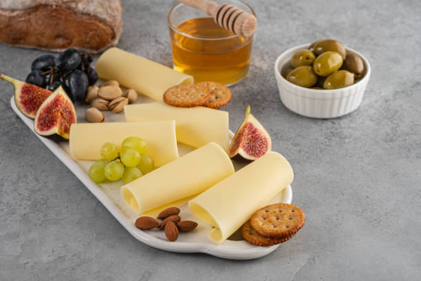 istock Cheese slices on white board with honey, figs, olives, grapes. 1173105944