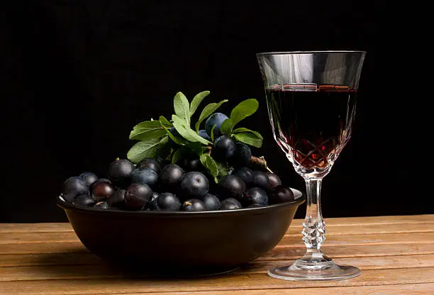 A Bowl of Sloe Berries beside a glass of Sloe Gin