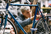 Young female employee repairing bicycle brake