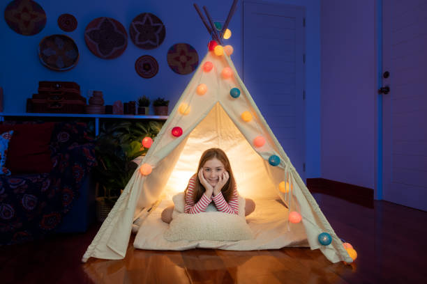 attraktive niedliche mädchen sitzen in tipi-zelt in ihrem schlafzimmer genießen glückliche zeit. - tipi bett stock-fotos und bilder