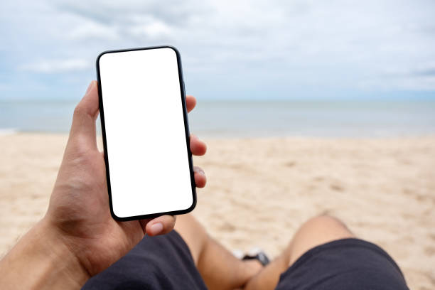istock a man's hand holding black mobile phone with blank desktop screen while laying down on beach chair 1173116306