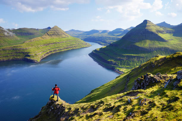 View on Funningur fjord. Eysturoy Island,  Faroe islands View on Funningur fjord from the Funningur top. Eysturoy Island, Faroe islands. Tourist in a red jacket explores natural attractions. Summer mountain landscape eysturoy photos stock pictures, royalty-free photos & images