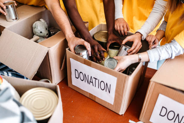 Teamwork in homeless shelter Small multi-ethnic group of people working on humanitarian aid project donation box stock pictures, royalty-free photos & images