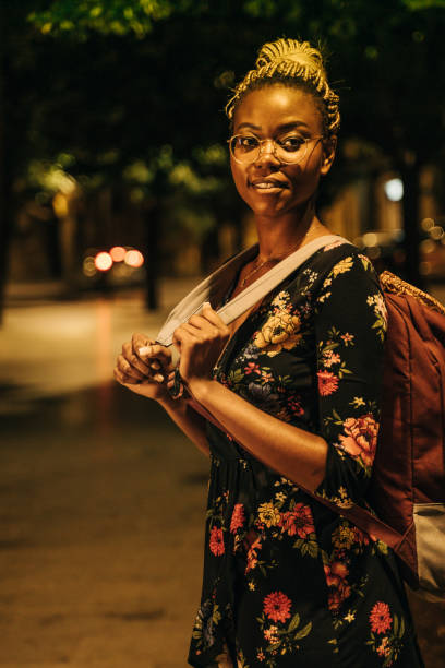 Young woman in the city at night carrying a backpack stock photo