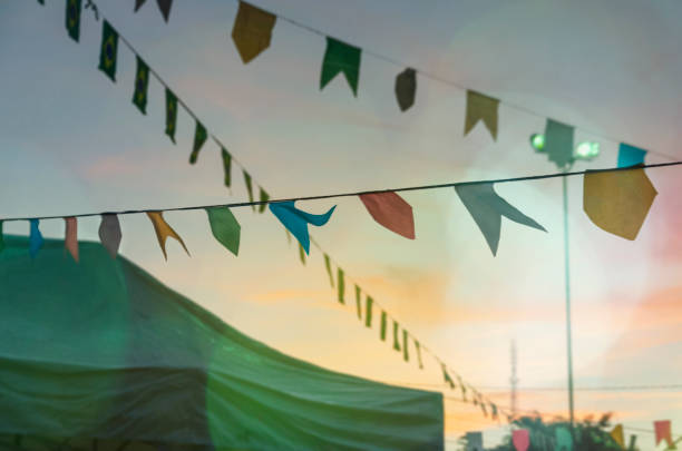 Decoration for June Party (Festa Junina), at sunset, with colourful paper pennants and Brazilian flags. Lighting with bokeh lens flare in different colors.