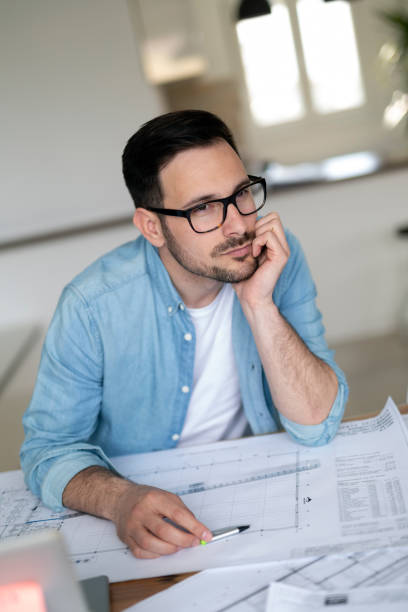 istock Thoughtful young architect man holding hand on chin and looking away 1173126171