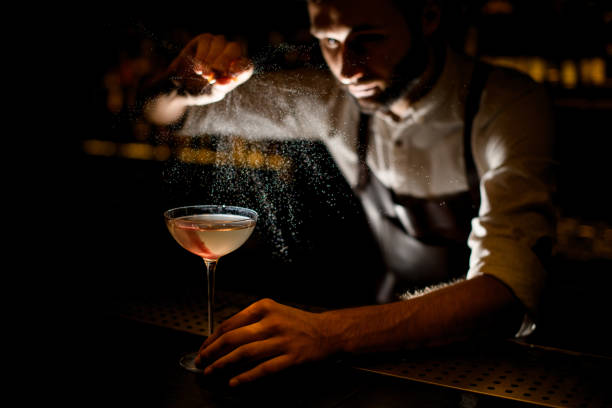 istock Attractive bartender serving a cocktail in the glass spraying on it with a lemon juice 1173130759