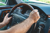 Male driver hands holding steering wheel. Man driving a car.