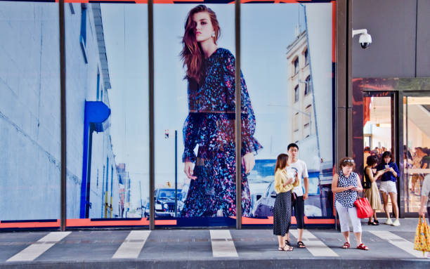 Fashion high street: Shoppers standing outside a clothing store displaying a huge ad board in Shenzhen Bay - China stock photo