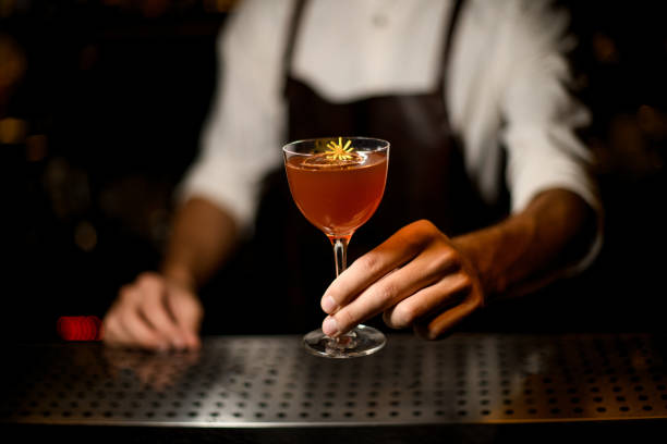 istock Professional bartender serving a cocktail in the glass with a caramelized lemon slice and a little yellow flower 1173133533