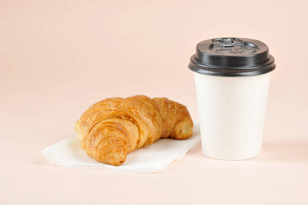 istock Coffee in a paper cup and a croissant on a light background. 1173133583