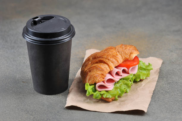istock Coffee in a black paper cup and a ham sandwich. 1173133672